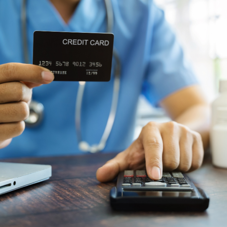 This is a doctor holding a credit card and using a calculator.