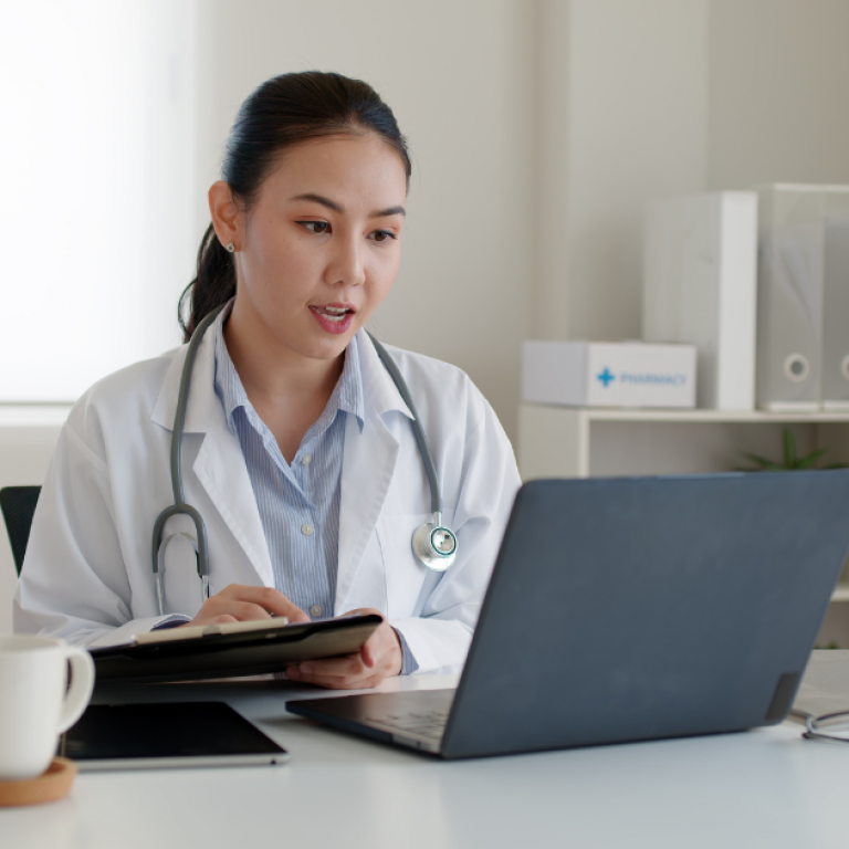 A doctor sitting at her desk looking at a computer
