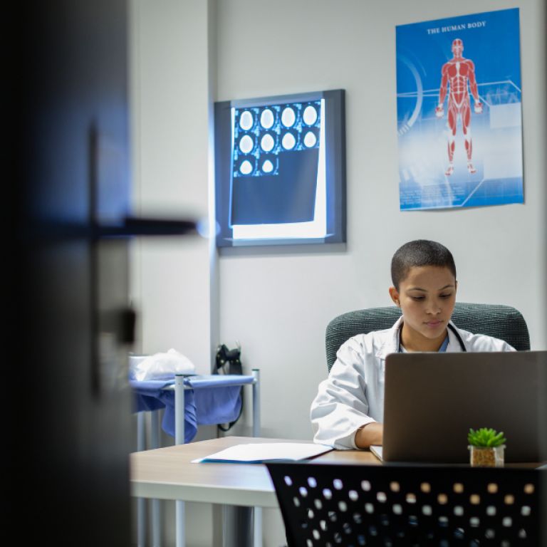 A doctor sitting at a desk looking at computer.