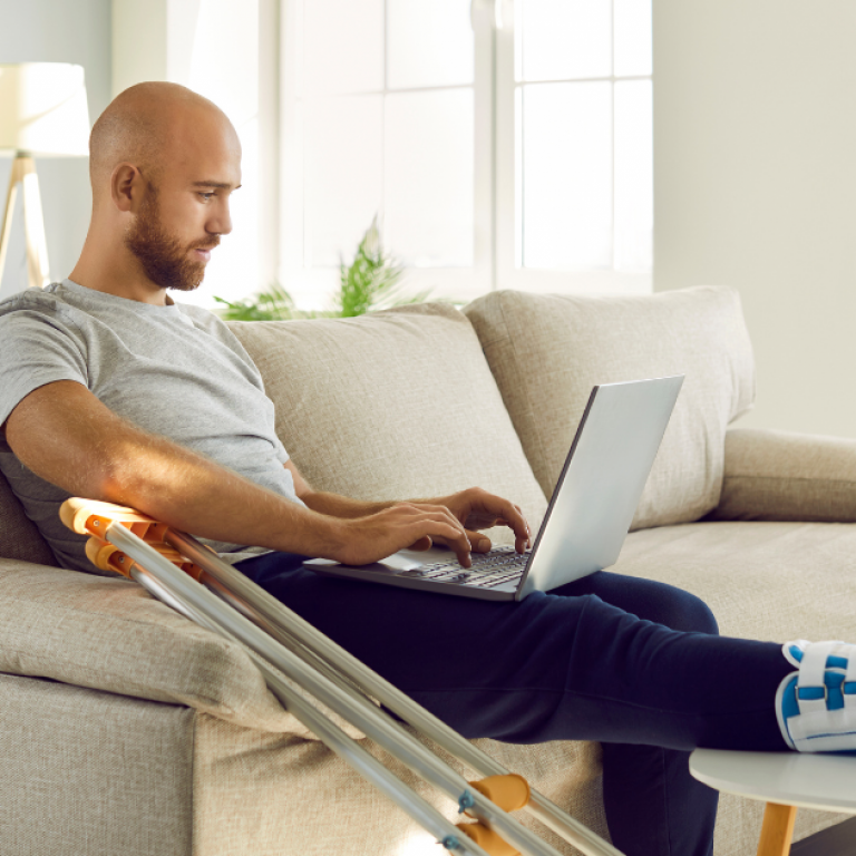 A man with an ankle brace looking at a laptop