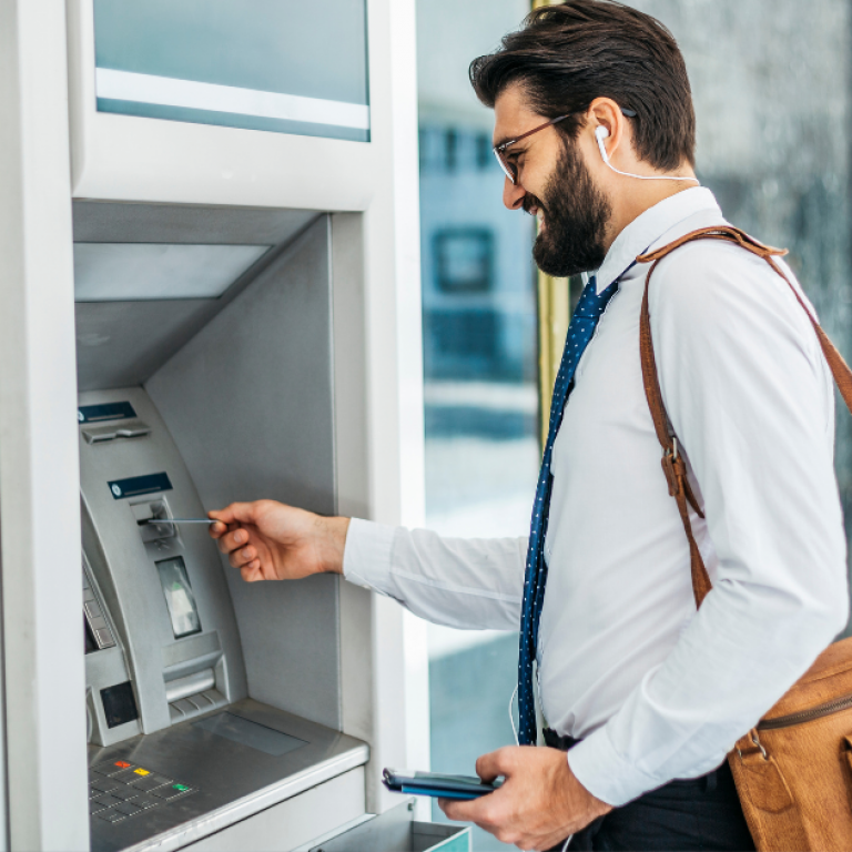 A man in professional clothing using an ATM